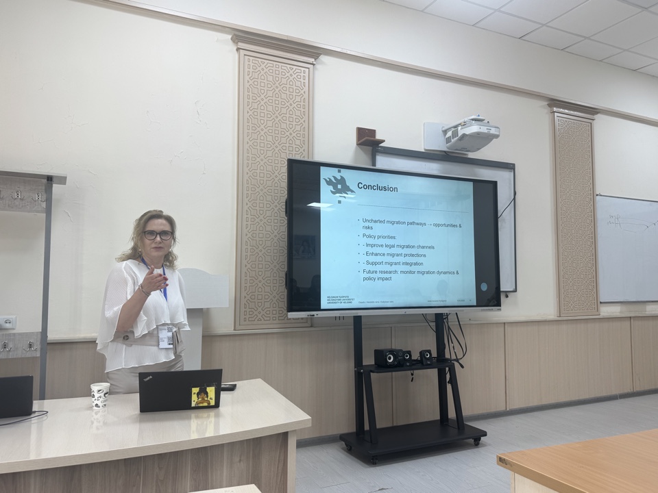 Larisa Kangaspuro infront of the class room and the screen delivering a presentation