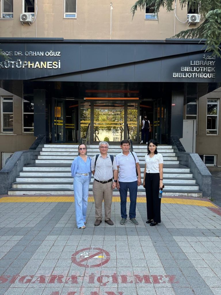 4 people posing in front of the building